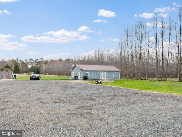 view of front facade with a shed, a front yard, metal roof, and an outdoor structure