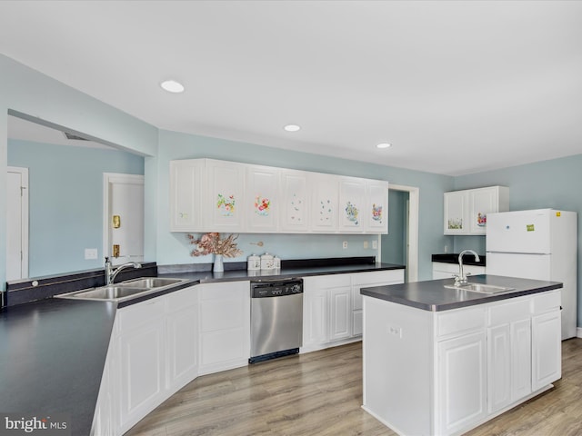 kitchen featuring light wood finished floors, stainless steel dishwasher, a sink, and dark countertops