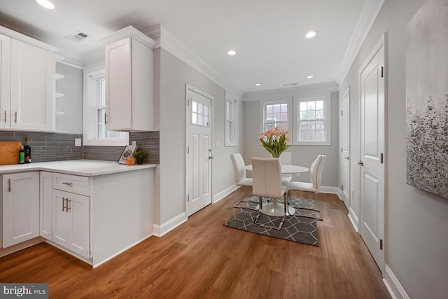 interior space with crown molding, visible vents, light wood-style flooring, and baseboards