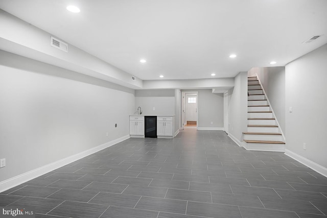 basement featuring indoor wet bar, baseboards, recessed lighting, stairs, and visible vents