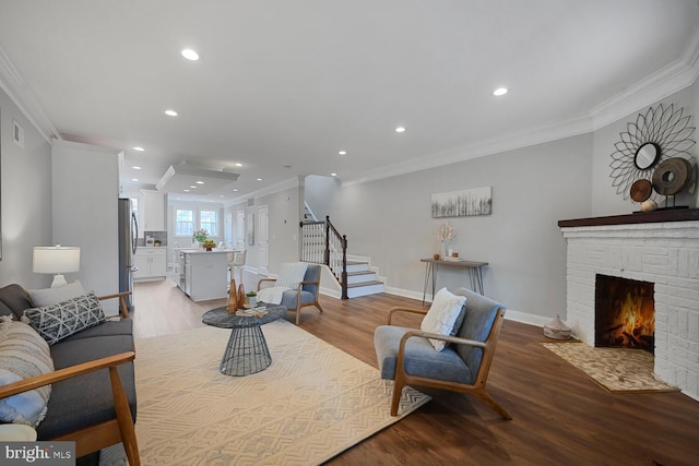 living area with baseboards, ornamental molding, recessed lighting, stairway, and light wood finished floors