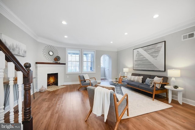 living room with arched walkways, wood finished floors, ornamental molding, and visible vents