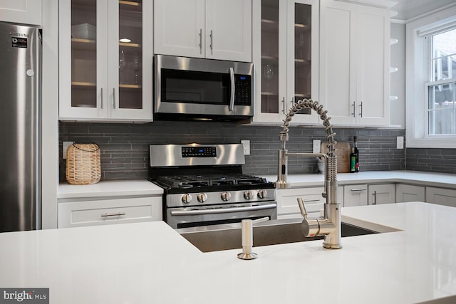 kitchen with decorative backsplash, light countertops, and stainless steel appliances
