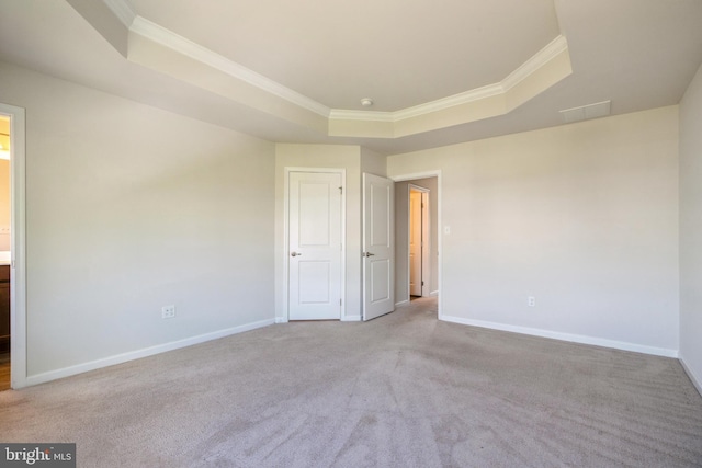 unfurnished room featuring a raised ceiling, carpet flooring, baseboards, and ornamental molding
