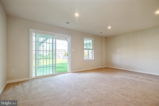 unfurnished room featuring light carpet, visible vents, and a healthy amount of sunlight