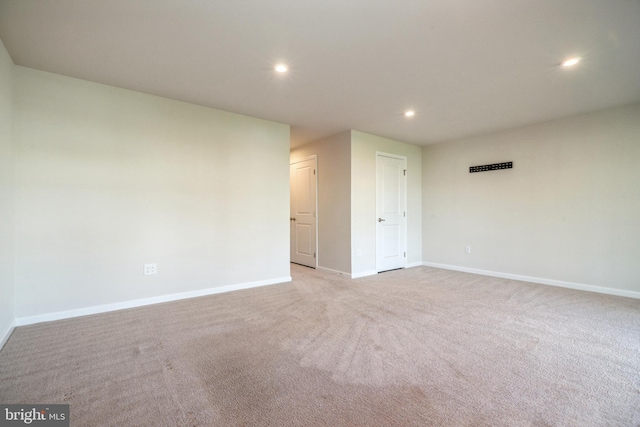 spare room with light carpet, recessed lighting, and baseboards
