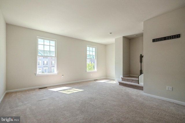 unfurnished room with stairway, carpet, visible vents, and baseboards