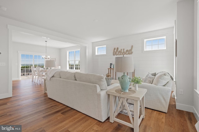 living room featuring a notable chandelier, baseboards, and wood finished floors