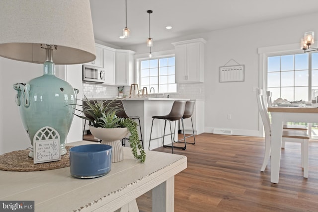 interior space with tasteful backsplash, visible vents, stainless steel microwave, and wood finished floors