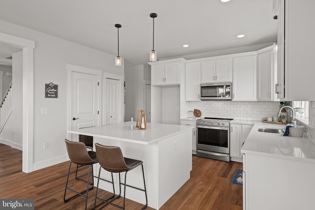 kitchen with a sink, stainless steel appliances, a center island, dark wood-style floors, and white cabinets