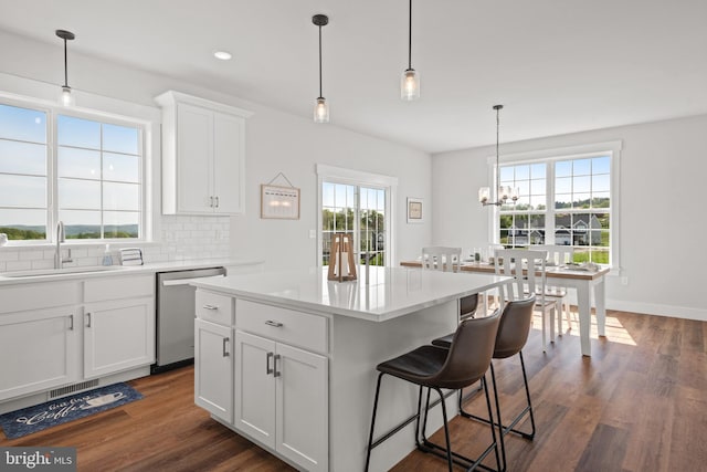 kitchen featuring a breakfast bar area, a sink, dark wood-style flooring, dishwasher, and decorative backsplash
