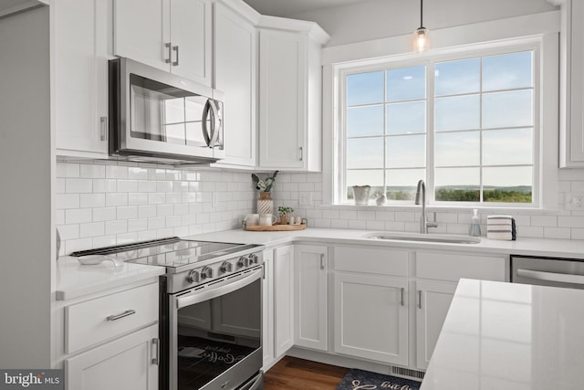 kitchen with white cabinets, light countertops, appliances with stainless steel finishes, and a sink