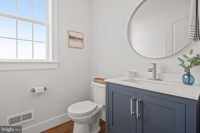 bathroom with toilet, plenty of natural light, visible vents, and wood finished floors