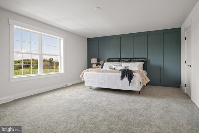 carpeted bedroom featuring a decorative wall and visible vents