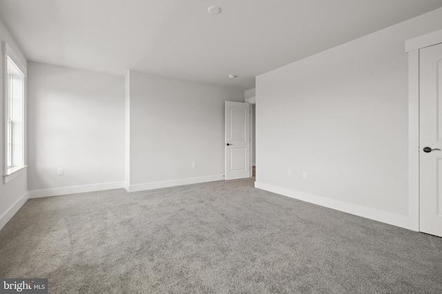 carpeted spare room featuring baseboards and plenty of natural light