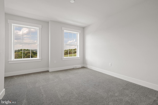 carpeted spare room featuring baseboards and visible vents