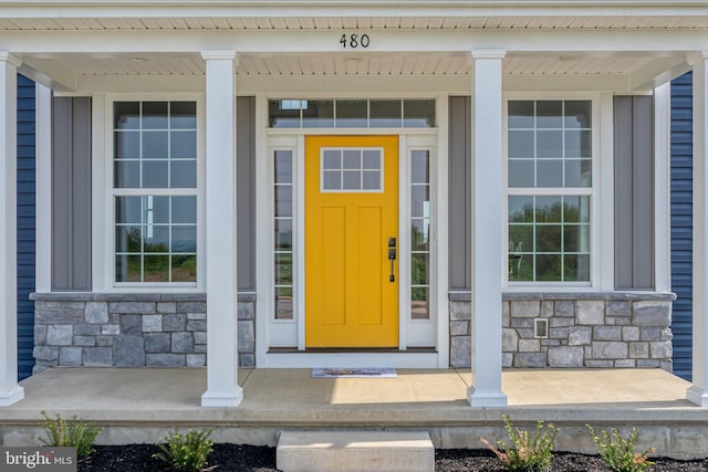 view of exterior entry featuring covered porch and stone siding