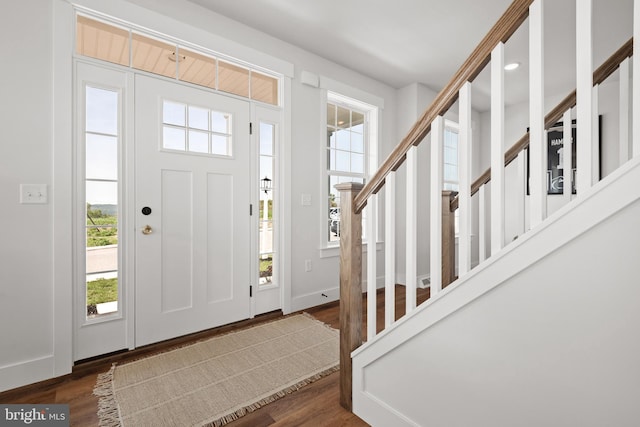 foyer entrance featuring baseboards, stairs, and wood finished floors