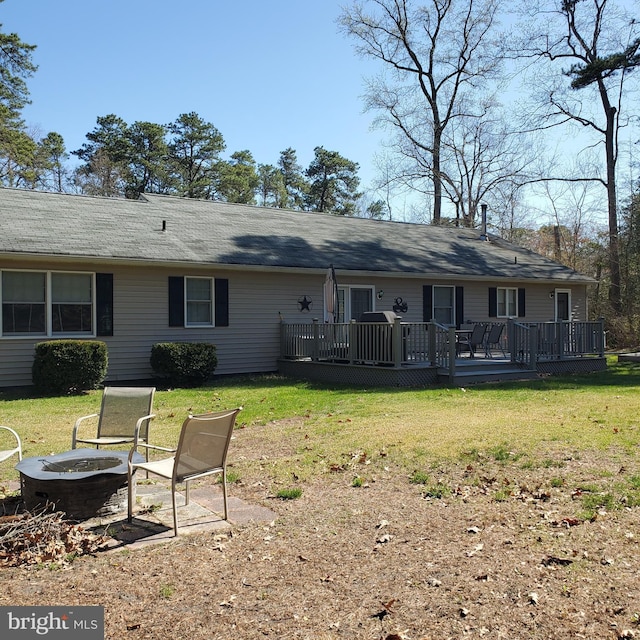 rear view of house with a lawn, an outdoor fire pit, and a wooden deck