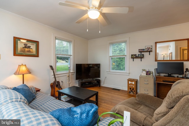 living room featuring a ceiling fan, ornamental molding, a healthy amount of sunlight, and wood finished floors