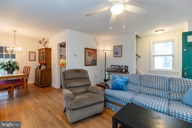 living room featuring baseboards, wood finished floors, and ceiling fan with notable chandelier