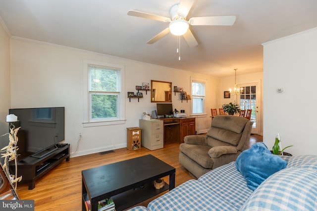 living area featuring light wood finished floors, baseboards, visible vents, ceiling fan with notable chandelier, and ornamental molding