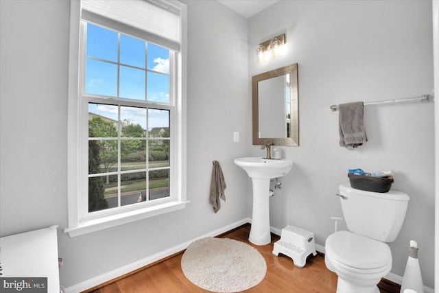 bathroom with toilet, baseboards, a sink, and wood finished floors