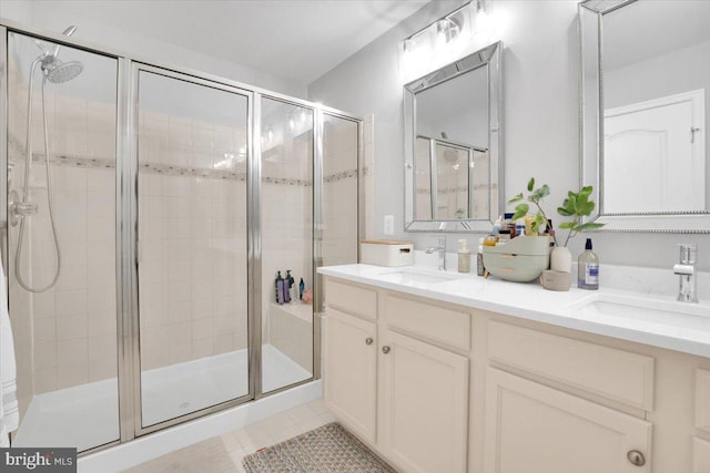 full bath featuring a sink, tile patterned flooring, double vanity, and a stall shower
