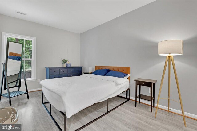 bedroom with baseboards, light wood-style flooring, and visible vents