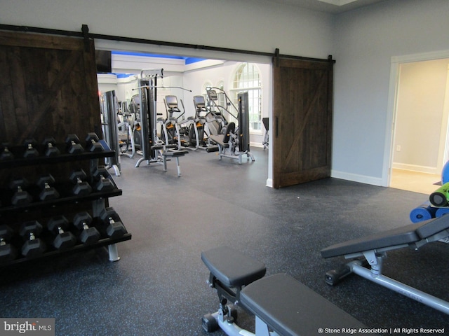 gym featuring baseboards and a barn door