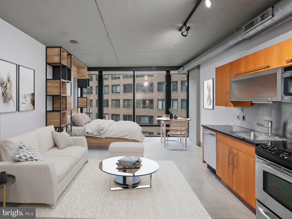 living area featuring floor to ceiling windows, rail lighting, and visible vents