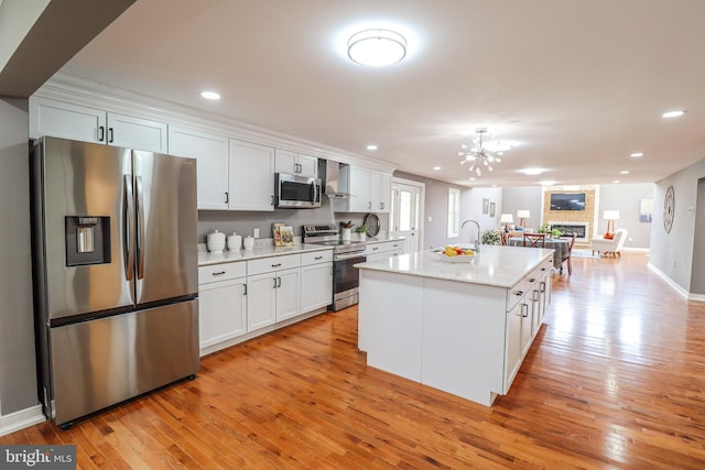 1111 S Mountain Rd, Dillsburg, PA 17019 - kitchen featuring appliances with stainless steel finishes, wall chimney range hood, a fireplace, light wood-style flooring, and recessed lighting