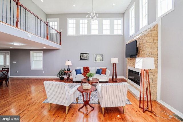 1111 S Mountain Rd, Dillsburg, PA 17019 - living room with a towering ceiling, a stone fireplace, wood finished floors, a chandelier, and baseboards