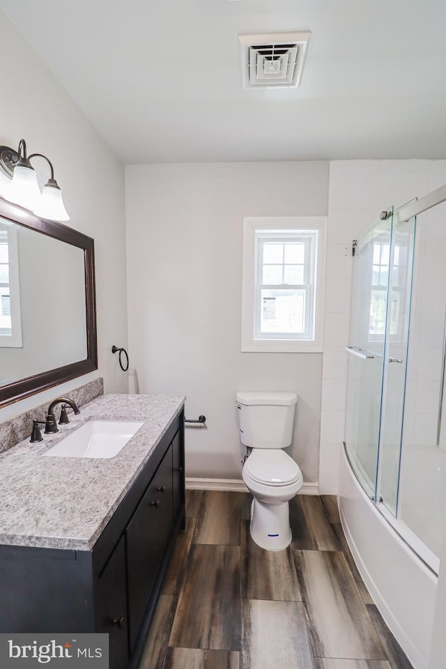 1111 S Mountain Rd, Dillsburg, PA 17019 - full bath with wood finished floors, toilet, vanity, shower / bath combination with glass door, and baseboards