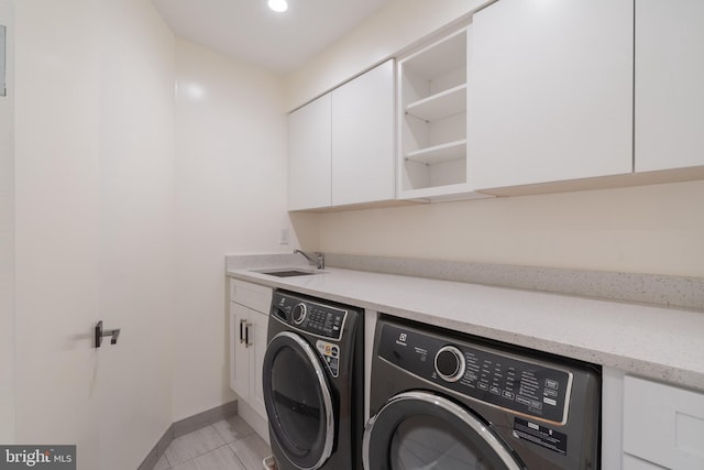 laundry area with light tile patterned floors, baseboards, separate washer and dryer, a sink, and cabinet space