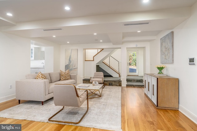 living area featuring light wood-style floors, recessed lighting, baseboards, and stairway
