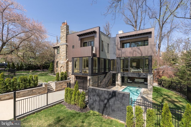 back of house with stone siding, stairway, a balcony, a fenced in pool, and fence private yard