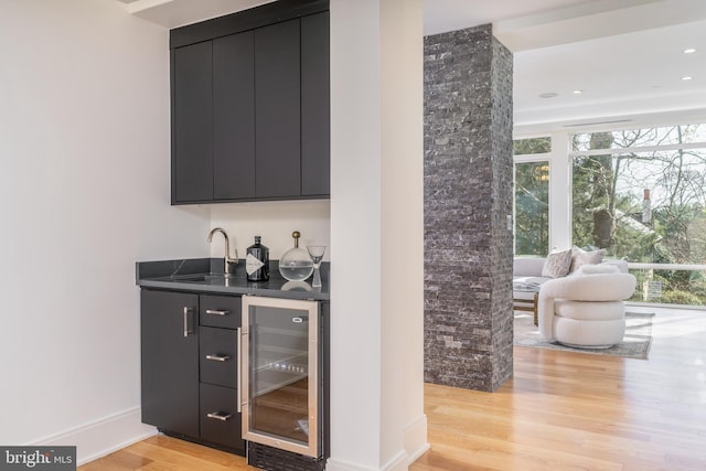 bar with a sink, wet bar, light wood-style flooring, and beverage cooler
