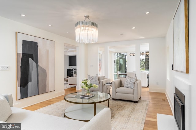 living room featuring light wood-style floors, recessed lighting, a notable chandelier, and baseboards