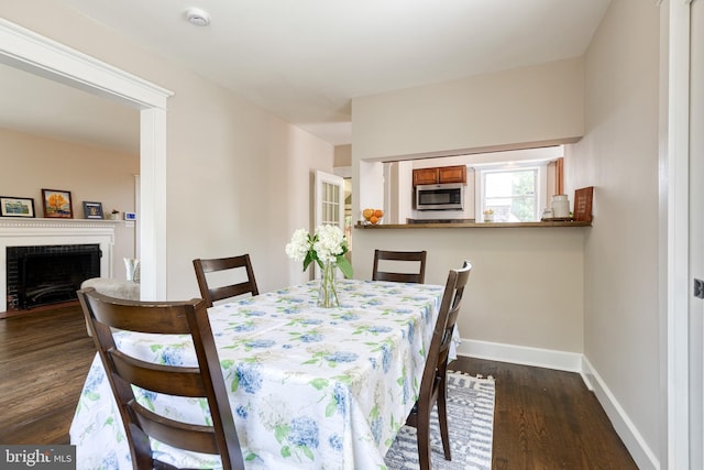 dining space featuring baseboards, dark wood-style floors, and a fireplace