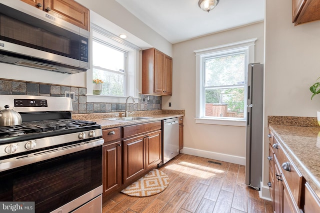 kitchen with stainless steel appliances, baseboards, a sink, and a healthy amount of sunlight