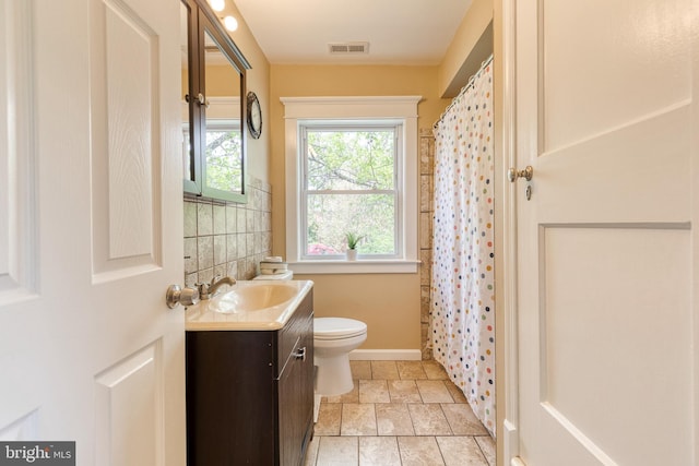 full bath with toilet, visible vents, baseboards, stone finish floor, and vanity
