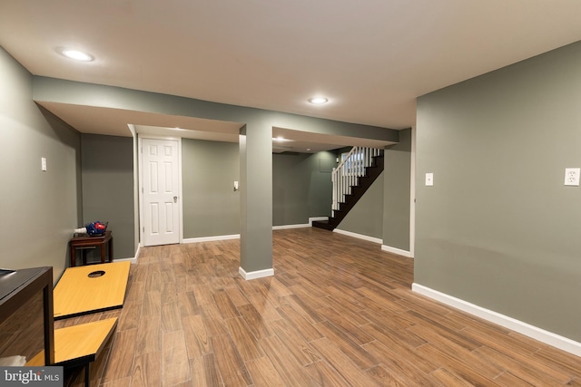 finished below grade area featuring stairway, baseboards, wood finished floors, and recessed lighting