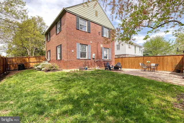 back of property with a patio area, a lawn, central air condition unit, a fenced backyard, and brick siding