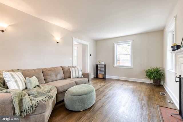 living area with baseboards, visible vents, and dark wood finished floors