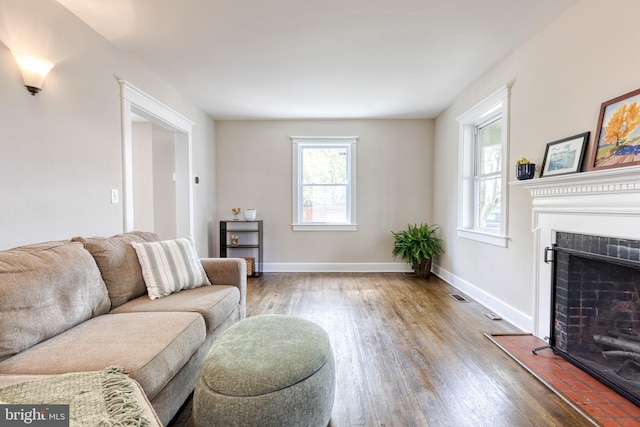 living area with a fireplace, wood finished floors, visible vents, and plenty of natural light