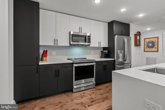1501 N 31st St Unit 318, Philadelphia, PA 19121 - kitchen with light wood-style flooring, tasteful backsplash, light countertops, and stainless steel appliances
