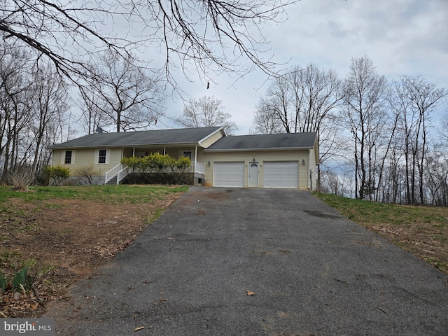 ranch-style home featuring an attached garage and aphalt driveway