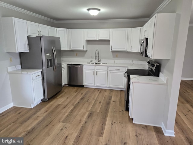 kitchen with light wood-style flooring, white cabinets, appliances with stainless steel finishes, light stone counters, and a sink