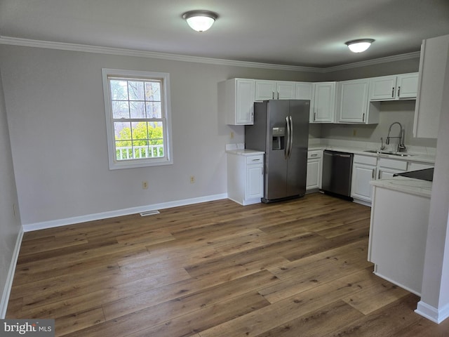 kitchen featuring a sink, ornamental molding, light countertops, dark wood-style floors, and stainless steel appliances